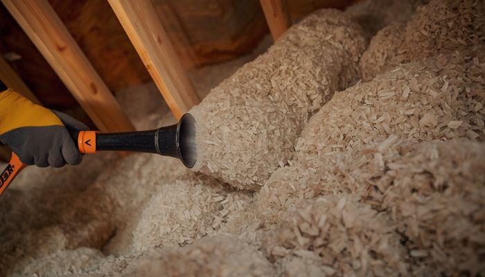 Cellulose insulation being blown into an attic space using a blowing machine and hose